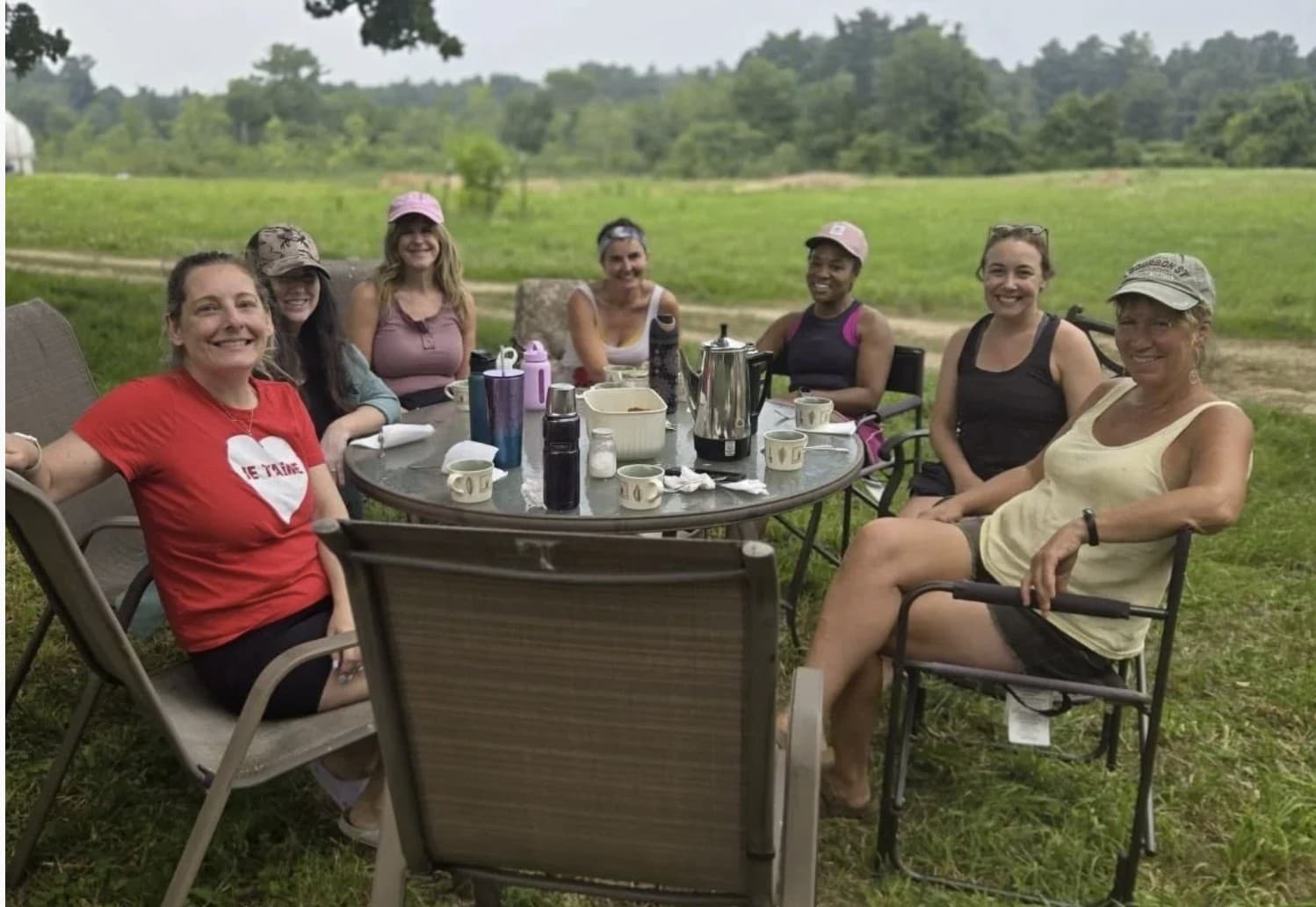 Members around a table in a field on a farm morning