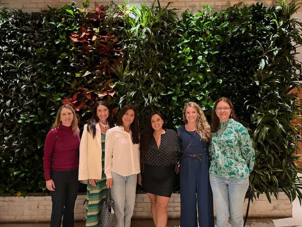 Members photographed in front of a living plant wall